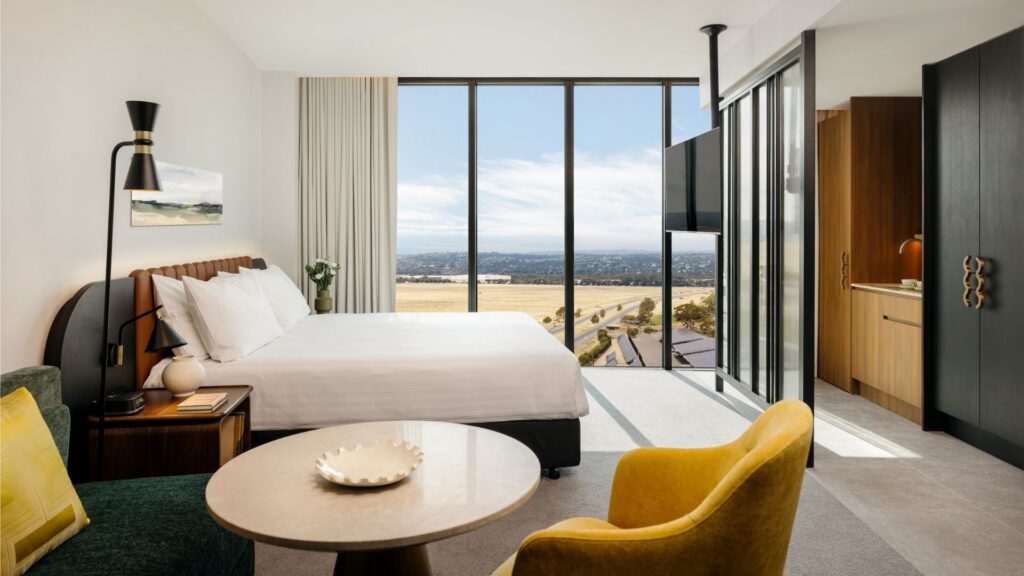 Contemporary guest room with king bed, lounge seating and floor-to-ceiling windows at Crowne Plaza Adelaide Mawson Lakes