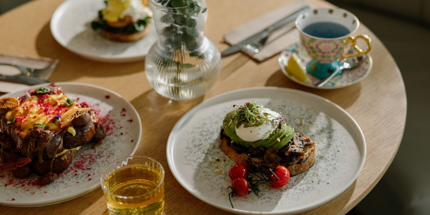 Plated breakfast dishes with avocado, poached egg and tea promoting the seniors buffet breakfast offer at Ember & Vine in Mawson Lakes, Adelaide